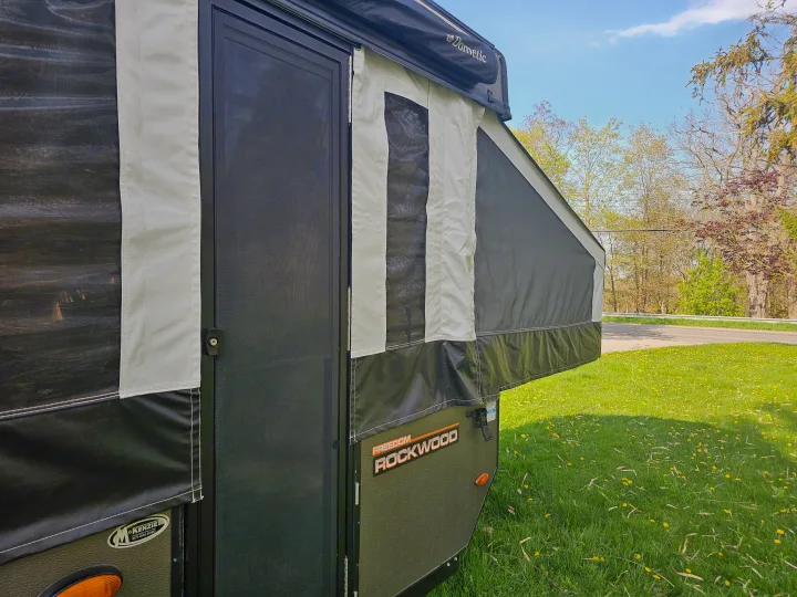 Pop-up RV rental: This Freedom Rockwood camper's side, with screened door & Dometic awning, ready for adventure on grass.. Forest River Rockwood LTD 2024