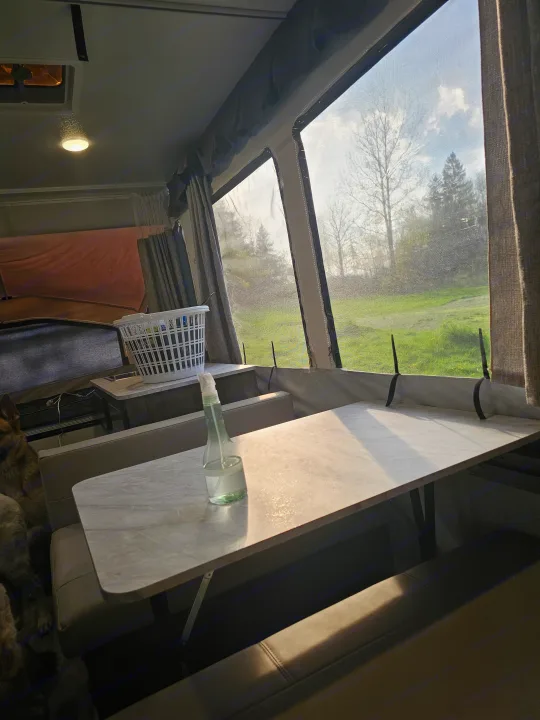 Inside this RV rental: Bright dining area with tables, benches, a dog, and a beautiful nature view. Ideal for camping.. Forest River Rockwood LTD 2024