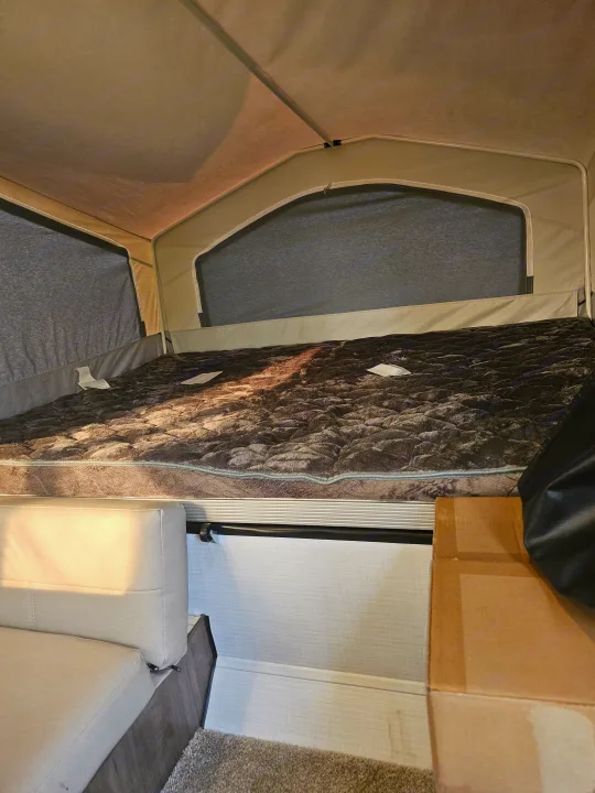 Cozy RV rental interior featuring a large pop-up bed, with an inviting sofa below, perfect for camping.. Forest River Rockwood LTD 2024