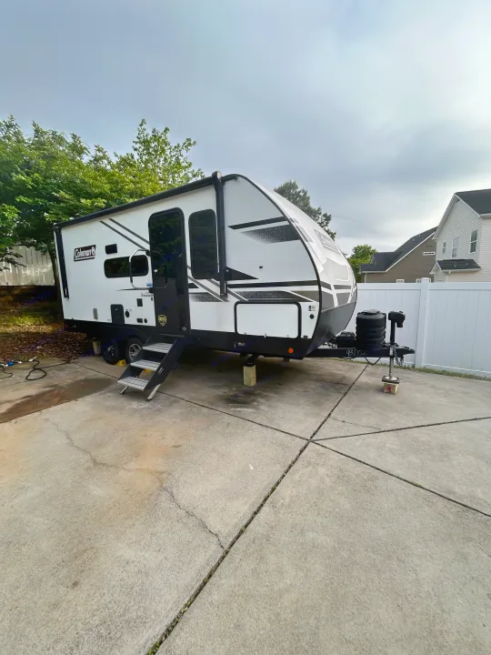 White & black Coleman travel trailer, an RV rental, parked on a driveway with steps.. 4YDTCMH25RJ935536 1805RB 2024