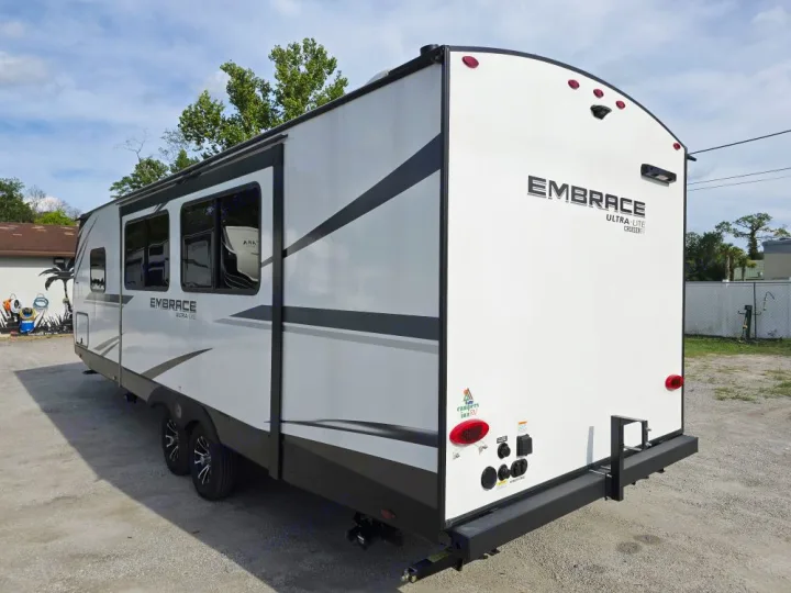 This white Embrace Ultra-Lite travel trailer, available for rv rental, highlights its sleek side profile, windows, and rear utility hookups.. Cruiser Embrace EL26RB 2024