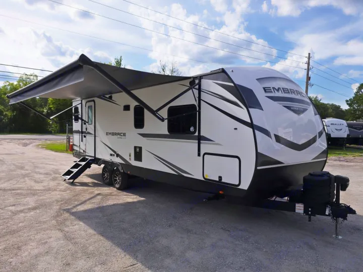 This white Embrace travel trailer, perfect for RV rental, features an extended awning and convenient steps.. Cruiser Embrace EL26RB 2024
