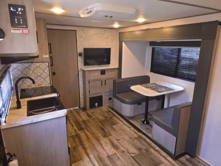 Fully equipped kitchen, cozy dinette, and entertainment setup are visible in this RV rental's interior.. Coleman 1855RB 2022