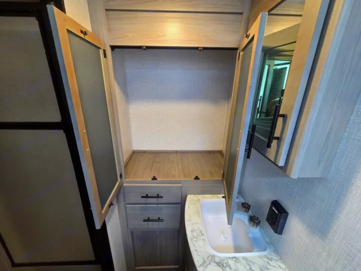 RV rental bathroom features: modern sink, open medicine cabinet with mirror, and spacious wood-toned wardrobe/closet.. Coleman 1855RB 2022