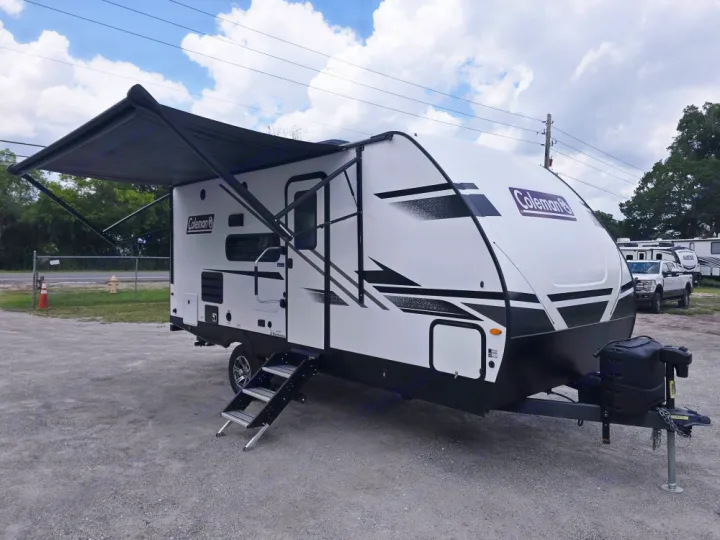 White Coleman travel trailer, an ideal RV rental, showcasing an extended awning & deployed steps for your next camping trip.. Coleman 1855RB 2022