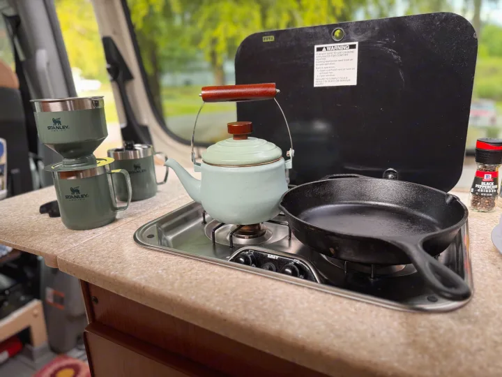 RV rental kitchen with a kettle, cast iron pan, Stanley coffee maker, and spice grinder for camping.. Sportsmobile Regular Body 2013