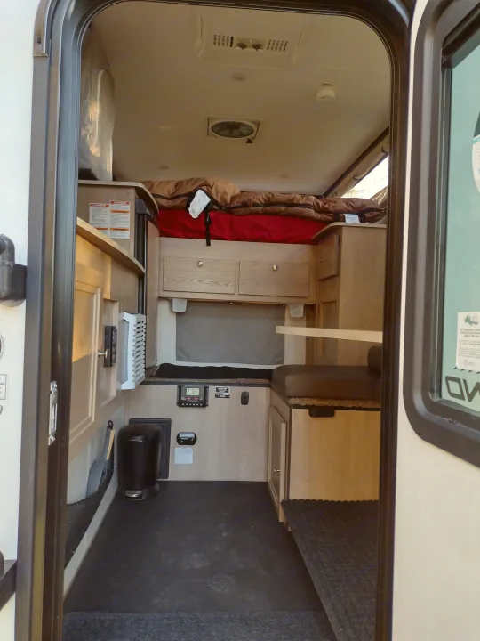 This RV rental interior offers a compact living space with a bed, dinette, and functional amenities.. Palomino Backpack Edition 2023