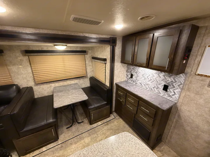 RV rental: Cozy dinette with dark benches & table, plus a kitchen counter with modern cabinets & herringbone backsplash.. Highland Ridge RV Light 2018