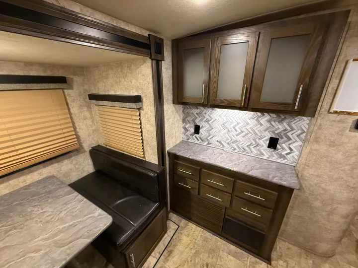 RV rental interior: A stylish dinette and kitchen area with dark wood cabinets and a herringbone backsplash.. Highland Ridge RV Light 2018