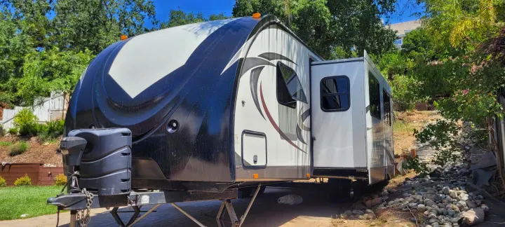 Sunny view of a black and white travel trailer RV with an extended slide-out, ready for rv rental and outdoor adventures.. Cruiser RV Radiance 2015