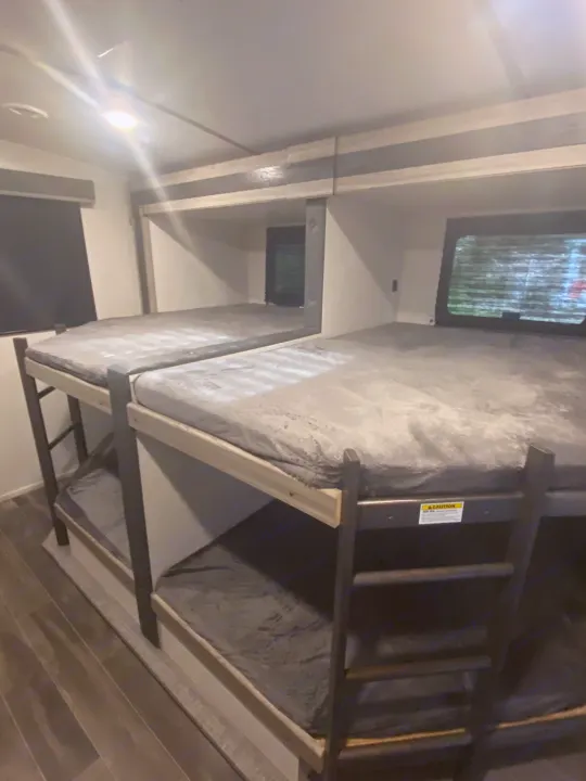 RV rental interior featuring four cozy bunk beds. Perfect for family adventures, offering comfortable sleeping spaces.. Keystone RV Passport GT 2022