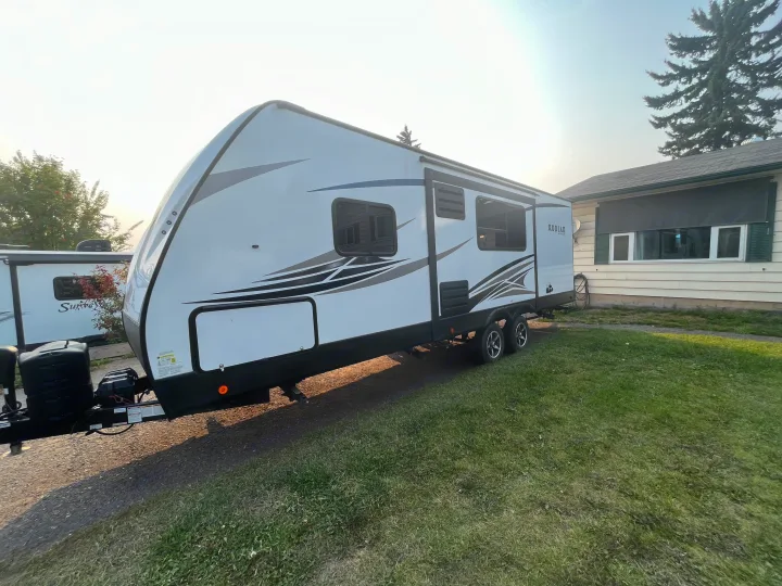 This white Kodiak Ultra Lite travel trailer RV rental is parked in a residential driveway on a sunny day.. Dutchmen Kodiak Ultra Lite 2020