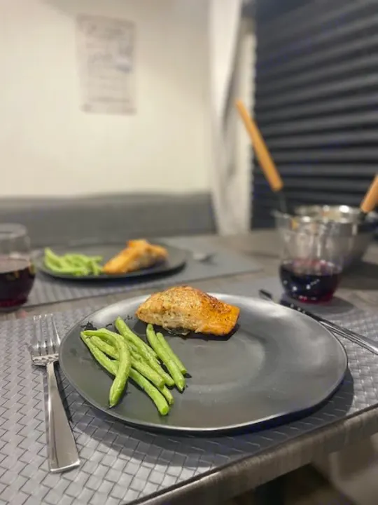 Two plates of salmon and green beans with wine, set for dinner in a cozy RV rental. Perfect for your next travel adventure.. Forest River Campsite Reserve 26CJ 2025