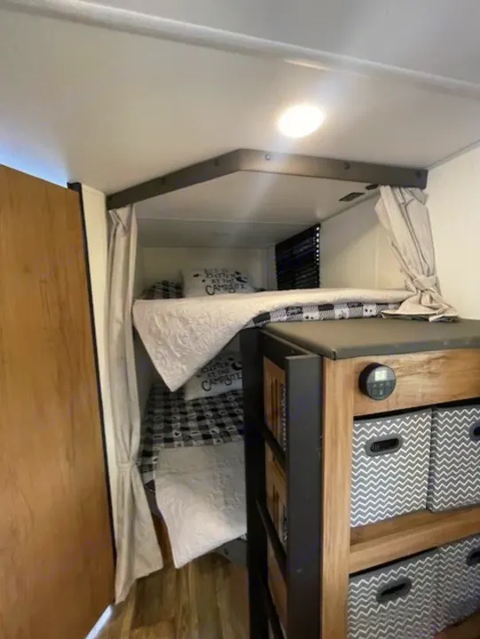RV rental interior showcasing cozy bunk beds with checkered bedding, privacy curtains, and handy storage.. Forest River Campsite Reserve 26CJ 2025