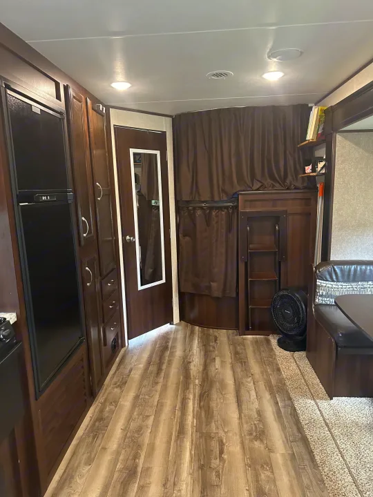 This RV rental interior features dark wood cabinets, a fridge, a bunk bed area, and a dinette.. Jayco Jay Flight 2018