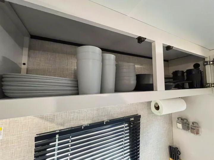 Neatly organized RV rental kitchen cabinets with light gray dishes, cups, bowls, and black cookware, ideal for travel.. Jayco Jay Flight SLX 170BHW 2025