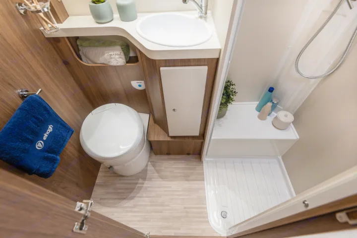 Compact RV rental bathroom featuring a toilet, sink, and a separate shower area, designed for efficient travel.. Elnagh baron 20 2025