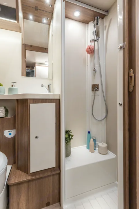 This compact RV rental bathroom features a sink, mirror, toilet, and separate shower, maximizing space and comfort.. Elnagh baron 20 2025