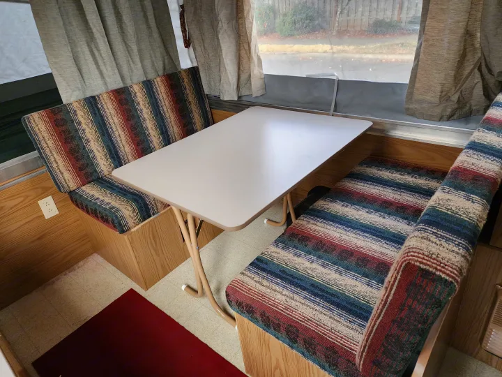 RV rental: Cozy pop-up camper dinette with striped cushions and a central table, ideal for compact dining.. Coleman Sedona 1999