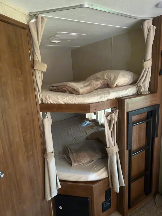 Cozy bunk beds in an RV rental, complete with privacy curtains and a ladder for easy access.. Gulf Stream Conquest 2017