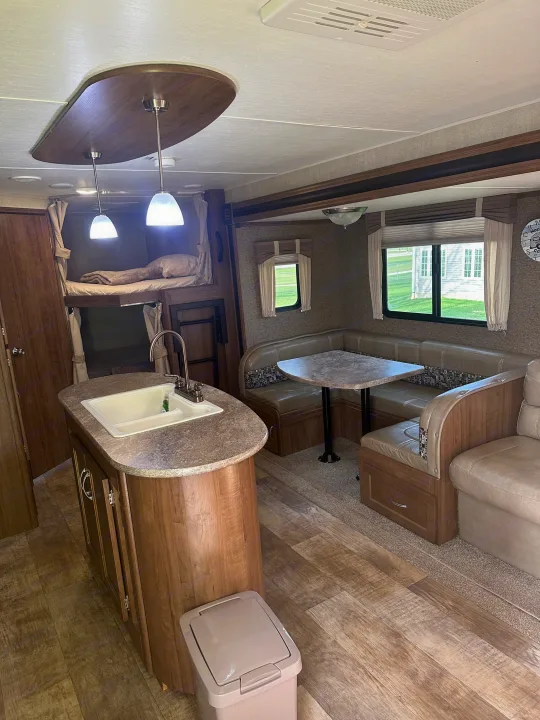 Spacious RV rental interior featuring a kitchen island, bunk beds, and a cozy dinette area.. Gulf Stream Conquest 2017