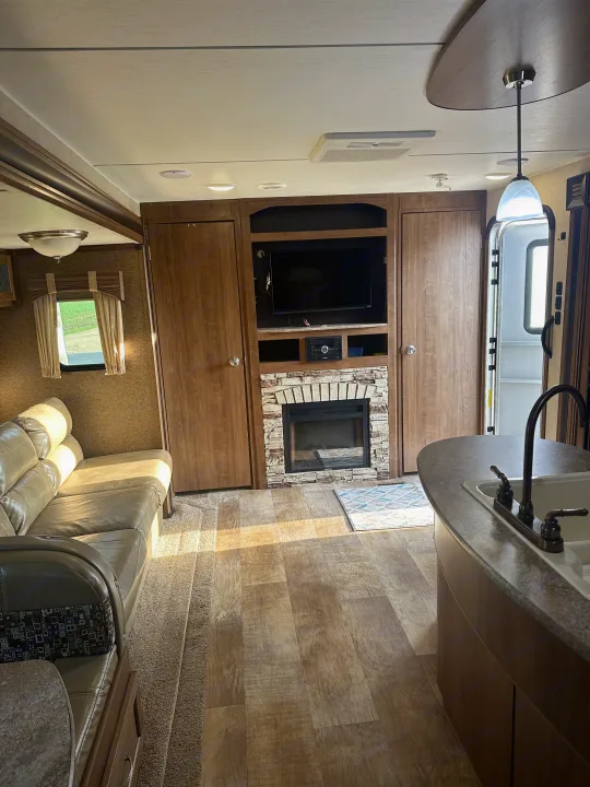 Spacious RV rental interior featuring a comfortable living area, fireplace, TV, and kitchen with ample natural light.. Gulf Stream Conquest 2017