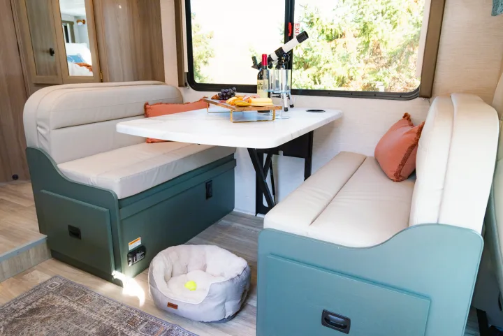 Inviting RV rental dinette with a charcuterie spread, wine, telescope, and a soft pet bed for travel.. Thor Motor Coach Eddie Bauer 21EBF 2025