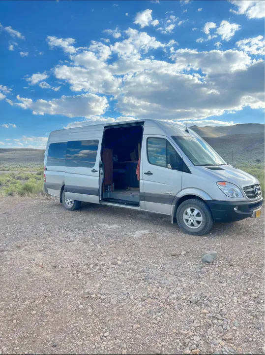Silver Mercedes Sprinter camper van, door open on a gravel lot, ready for your rv rental adventure or camping trip.. Mercedes Sprinter 2008