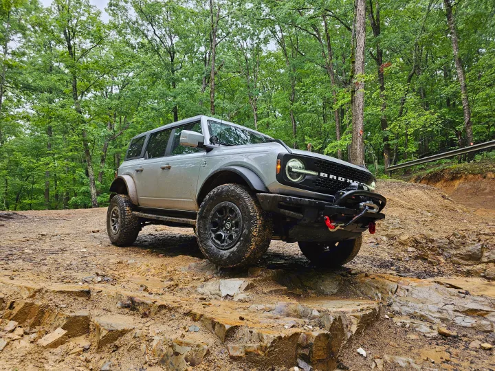 Grey Ford Bronco conquers a rocky, muddy forest trail. A rugged adventure, quite different from an RV rental vacation.. Ford Bronco Outer Banks 2022