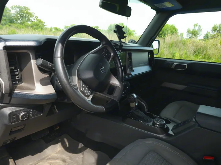Driver's seat view of a rugged vehicle interior, ready for any rv rental adventure. Steering wheel, dashboard, and gear controls visible.. Ford Bronco Outer Banks 2022
