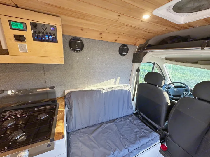 Cozy rv rental campervan interior with wood ceiling, integrated control panel, galley kitchen, and modular bed/seating.. Dodge Promaster 3500 2020
