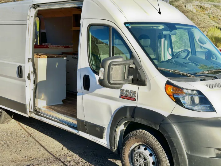White Ram ProMaster camper van with side door open, revealing custom interior. Explore in style with this RV rental.. Dodge Promaster 3500 2020