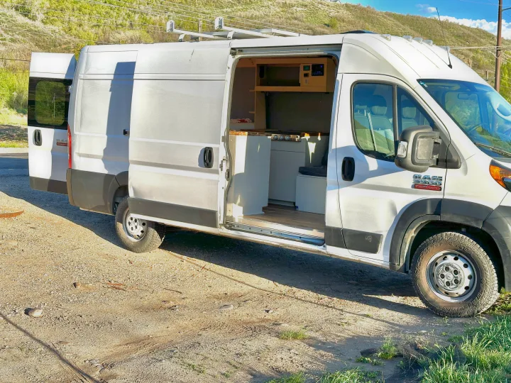 White Ram ProMaster camper van conversion, side door open to show kitchenette and interior setup.. Dodge Promaster 3500 2020
