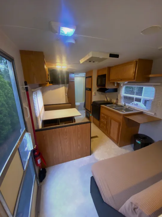 This RV rental interior features a kitchen (right), central dinette, and a bed in the foreground, offering a complete living space.. Dutchmen Express 2001