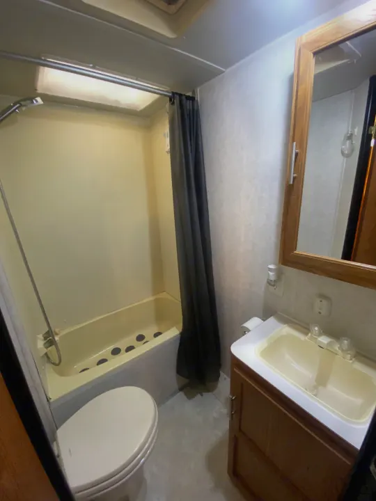 Inside an RV rental: a compact bathroom with a shower, bathtub, toilet, and sink vanity, perfect for travel.. Dutchmen Express 2001