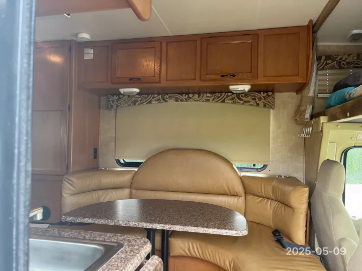 Inside this RV rental: a bright interior with a U-shaped dinette, full kitchen, wood cabinets, and a bunk bed area.. Coachman Freelander 2013