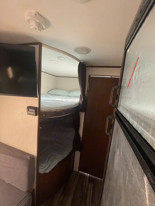 RV rental: Cozy travel trailer interior showcasing bunk beds, a TV, sofa, and refrigerator. Designed for compact living.. Jayco Jaycoflight 2017