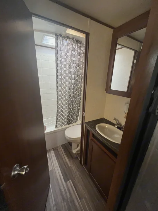 Inside a functional RV rental bathroom: view of a white shower/tub, toilet, and a dark vanity with a light sink basin.. Jayco Jaycoflight 2017