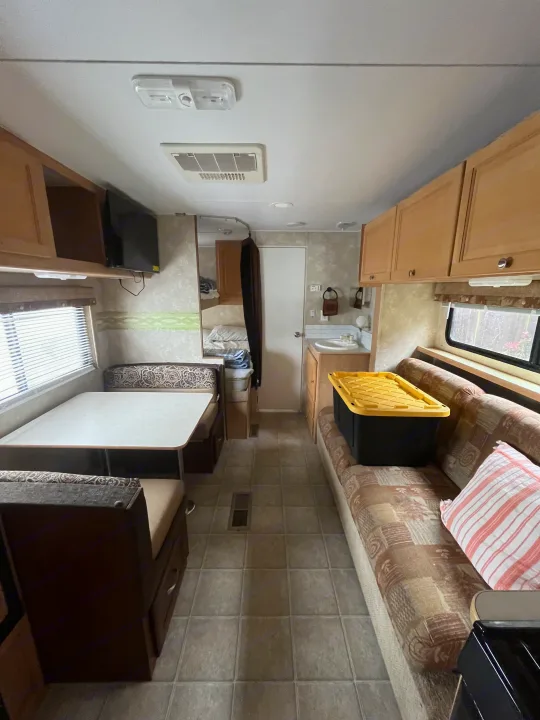 RV rental interior: A compact living space featuring a dinette, sofa, cabinets, and small kitchen sink.. Thor Motor Coach Wave 2007