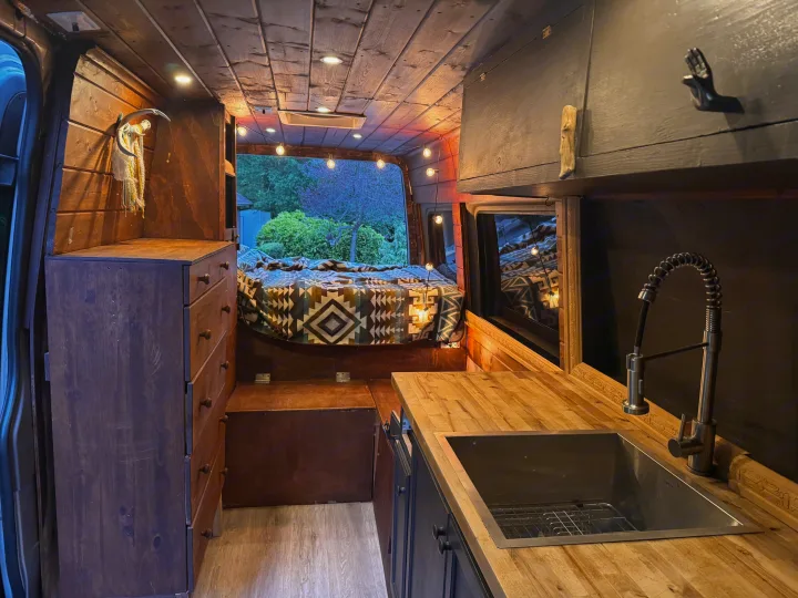 Step inside this charming RV rental: a rustic wooden camper van conversion featuring a bed, kitchen, and ambient lighting.. Mercedes Sprinter 2008