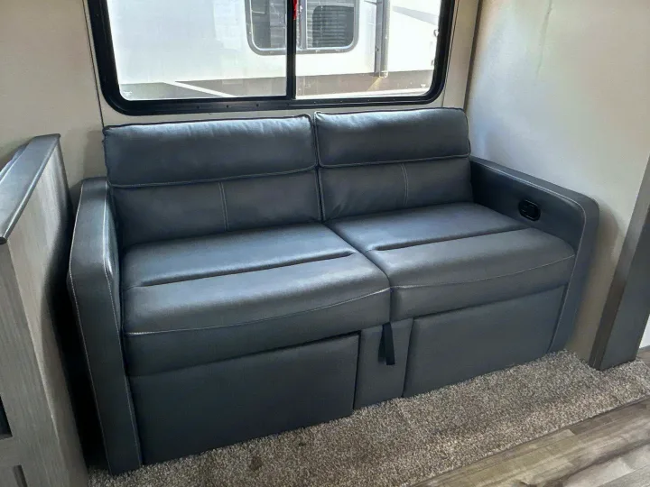 Comfortable gray sleeper sofa in an RV rental, featuring recline controls and pull-out extension for extra sleeping space.. Coleman Lantern 2022