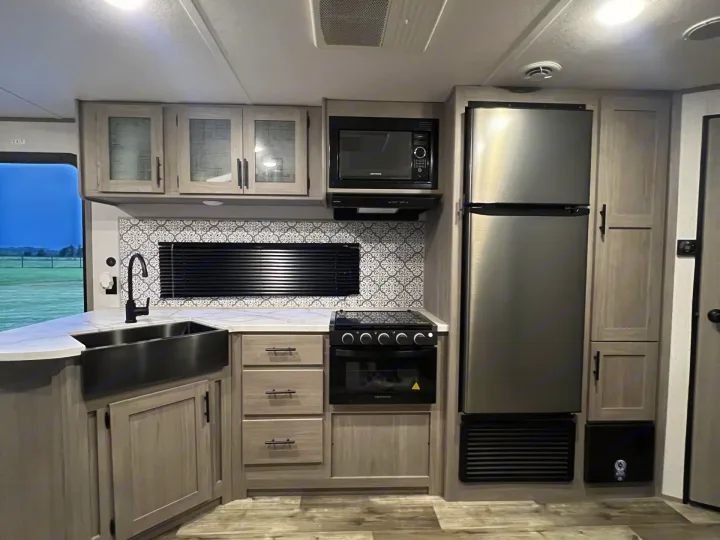 Explore this modern rv rental kitchen with light cabinets, black farmhouse sink, stainless fridge, stove, microwave, and patterned backsplash.. Coleman Lantern 2022