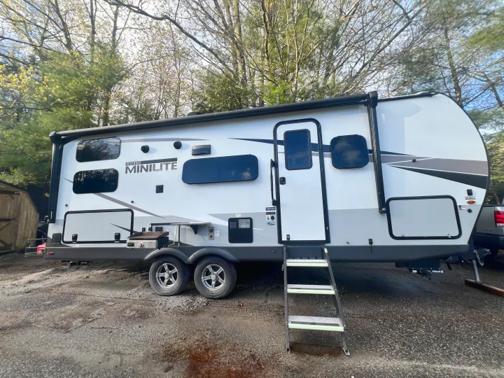 A modern Rockwood Mini Lite RV rental, featuring an outdoor grill, ready for comfortable travel and camping trips.. Forest River Rockwood Mini Lite 2023