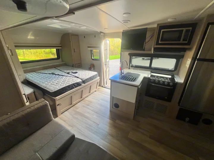 Explore this RV rental's cozy interior: bed, kitchen with sink & stove, TV, and couch for relaxing.. Forest River Rockwood Mini Lite 2023