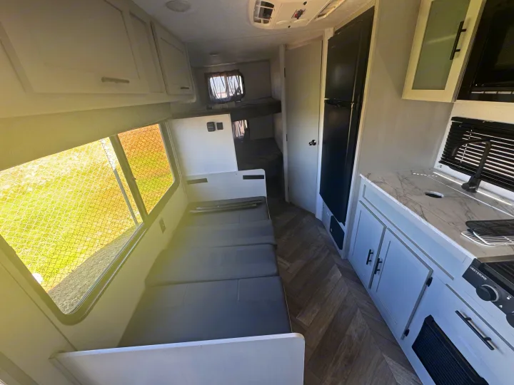 Inside this RV rental: a modern kitchen, convertible dinette, and bunk beds for travel comfort.. Forest River Wildwood FSX 2021