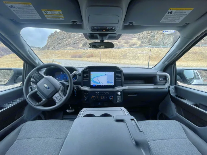 Spacious rental truck interior: dashboard, steering wheel, navigation, ideal for an RV rental road trip.. Ford Ford F150 2024
