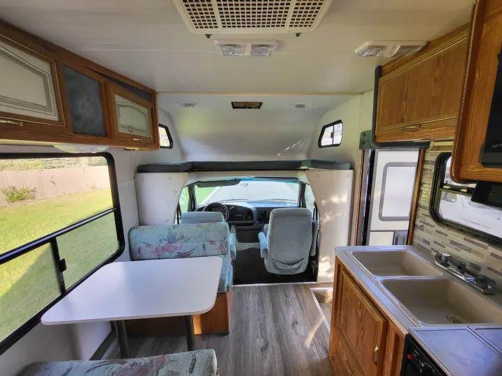 Well-equipped RV rental interior showcasing a dinette, kitchen with sink, and driver's area, ready for adventure.. Ford Econoline 1992