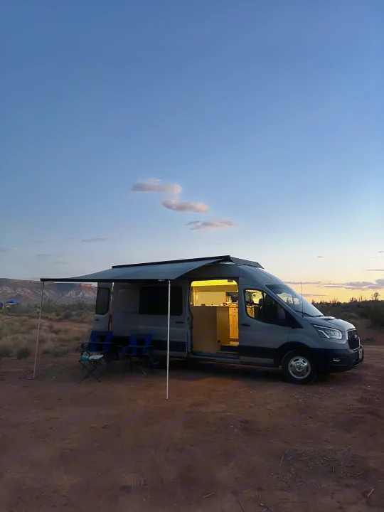 Relaxing campsite setup with an RV rental at sunset. Enjoy the open road and van life adventures.. Ford Transit 2022
