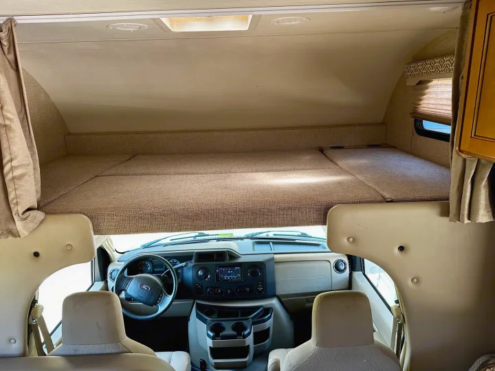 Inside an RV rental: a cozy overhead bed above the Ford driver's cockpit, ready for adventure.. Thor Freedom Elite 2017
