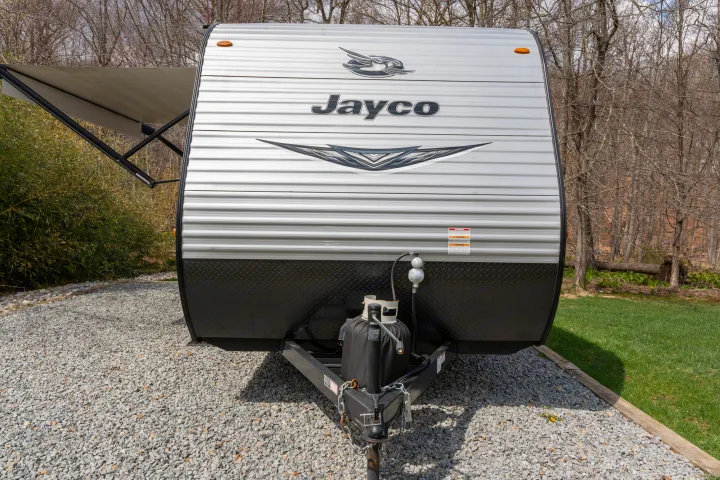 Front view of a Jayco travel trailer RV rental parked on gravel with an extended awning, ready for your outdoor adventure.. Jayco Jay Flight 2021